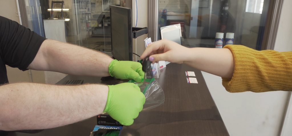 Customer dropping key into bag held open by staff member