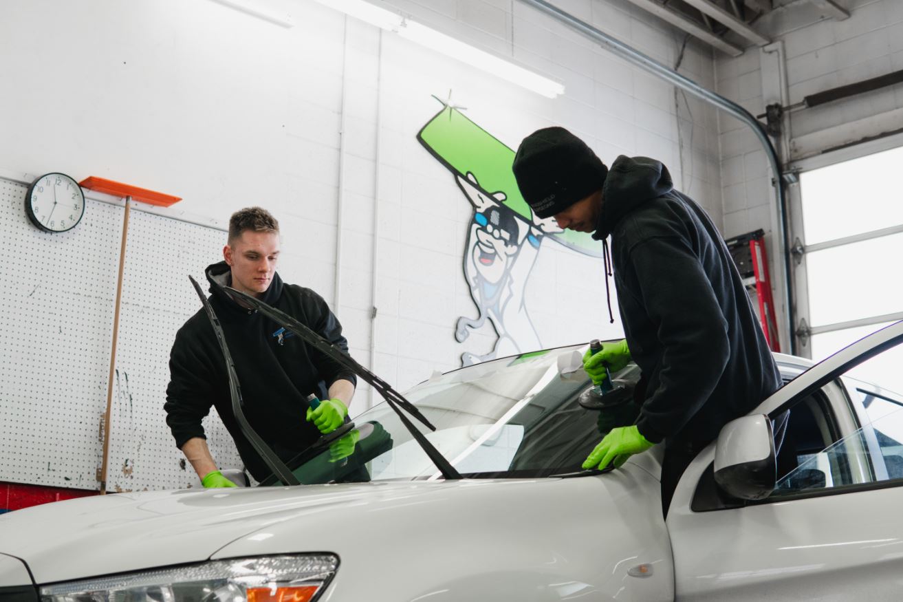 Auto Glass windshield being set into vehicle during replacement